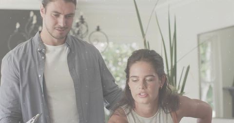 Couple planning meal in minimalist kitchen woman leaning at island as partner using tablet