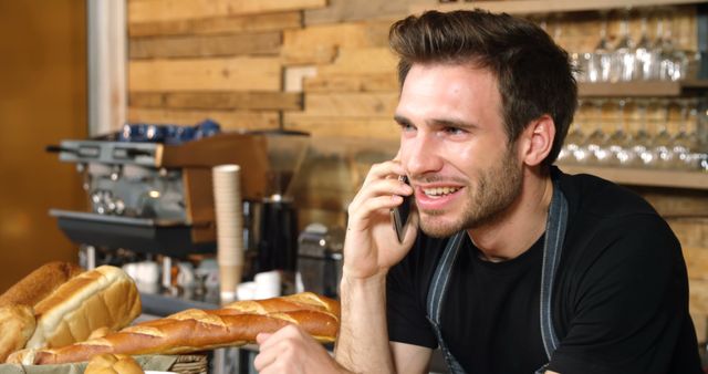 Smiling Male Cafe Worker Taking Phone Call in Rustic Bakery Setting - Download Free Stock Images Pikwizard.com