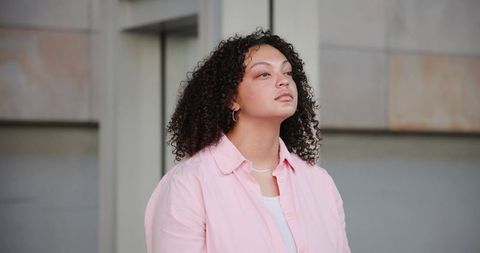 Contemplative african american woman gazing upward against modern urban concrete facade