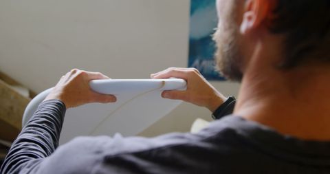Surfboard Maker Inspecting Board in Workshop