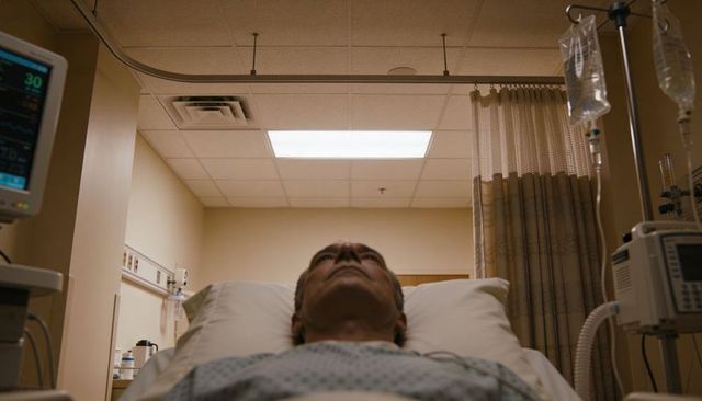 Senior man lying in hospital bed with iv pole and monitor, clinical patient care scene
