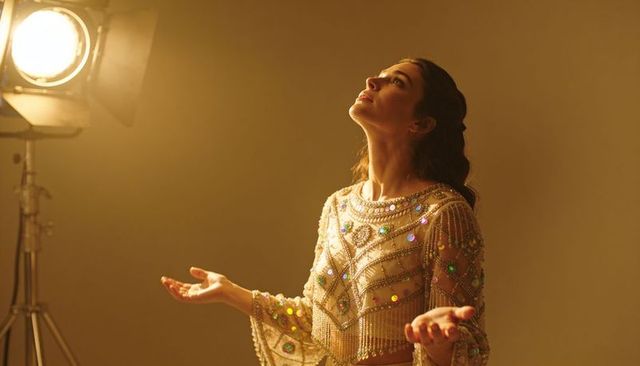 Glamorous woman wearing beaded sequin fringe top basking in dramatic studio spotlight