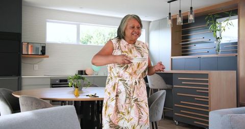 Senior Woman Joyfully Dancing in Modern Kitchen with Fruit