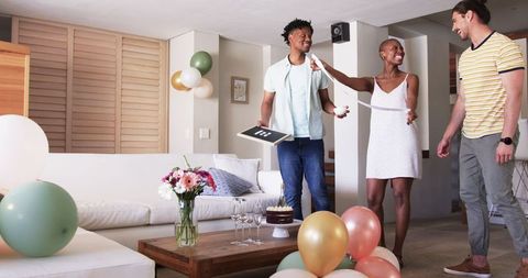 Friends preparing birthday celebration at home with balloons and cake