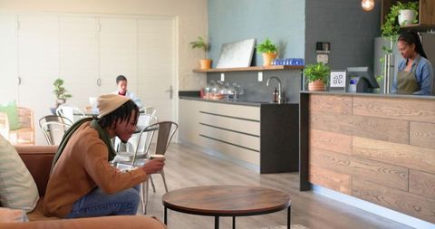 Young african american man sipping coffee in sunlit cozy urban cafe with barista