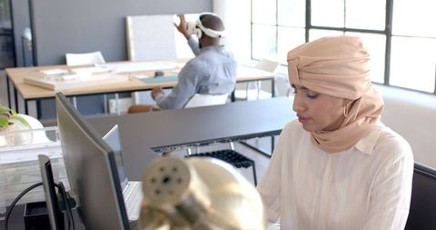 Focused woman in hijab working on computer in modern office