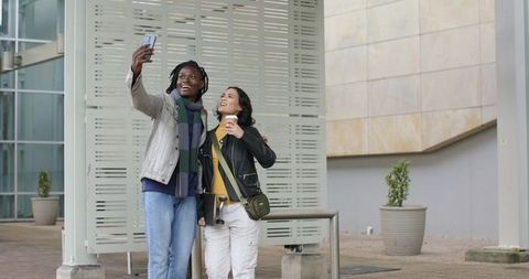 Smiling Couple Taking Selfie with Coffee in Urban Plaza, Casual Street Fashion and City Architecture
