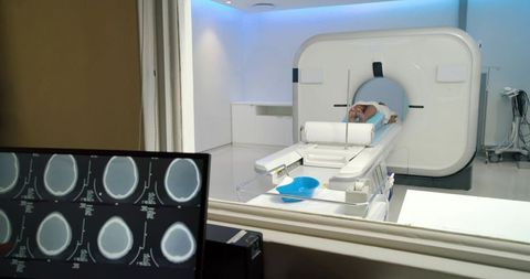 African american woman undergoing ct scan in modern radiology suite with brain scan monitor