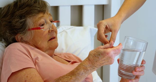 Elderly Woman Receiving Assistance with Medication in Bed - Download Free Stock Images Pikwizard.com