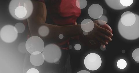 Athlete holding football at chest with strong grip and bokeh lights, gridiron focus action