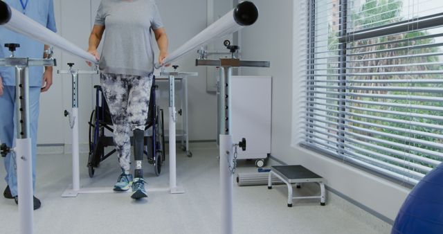 Older woman in rehab clinic walking with support of parallel bars, likely engaging in physical therapy or rehabilitation exercises. Clear light from large window. Could be used for healthcare, physical therapy services, rehabilitation clinic advertisements, or informational content on recovery and mobility improvement.