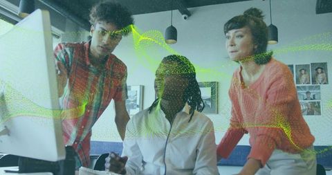 Diverse team analyzing data on computer monitor in modern office