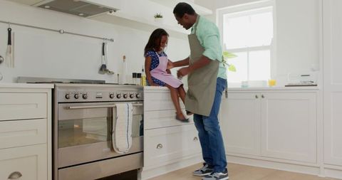 Father Helping Daughter in Kitchen During Meal Preparation