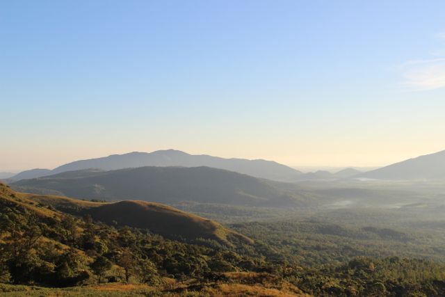 Panoramic view of mountain range under clear sky during dawn. Ideal for nature and travel themes, this scenic landscape captures the calmness and natural beauty of morning light over rolling hills and valleys. Suitable for brochures, travel blogs, posters, and websites that emphasize tranquility, nature vacations, hiking, or ecological awareness.