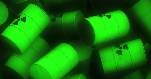 Pile of glowing green radioactive barrels
