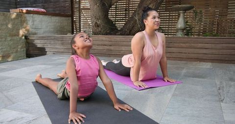 Mother and Daughter Practicing Yoga Outdoors on Stone Patio