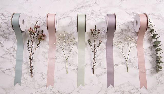 Pastel satin ribbon flatlay with botanical sprigs on marble for gift wrap and crafts