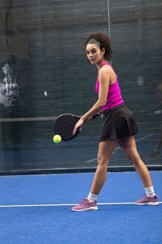 African american padel player hitting ball on indoor blue court