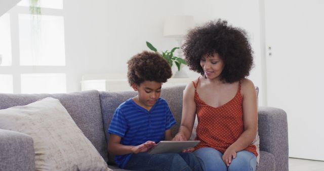 Mother and son using digital tablet on living room couch - Download Free Stock Images Pikwizard.com