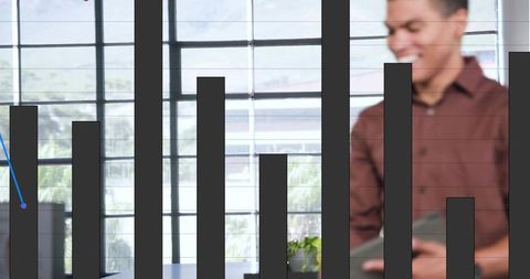 Businessman holding tablet by metal-framed windows with overlaid bar chart and dashboard