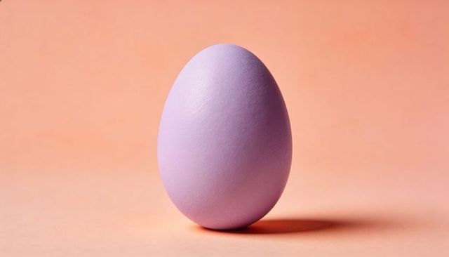 Standing pastel lavender egg casting soft shadow on peach surface minimalist still life