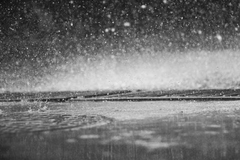 Close-up of rain falling on wet street surface in black and white