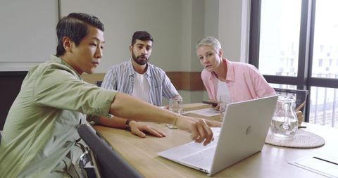 Diverse Team Collaboration Around Laptop at Modern Office