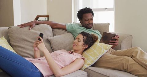 Multiracial Couple Relaxing with Technology on Cozy Sofa