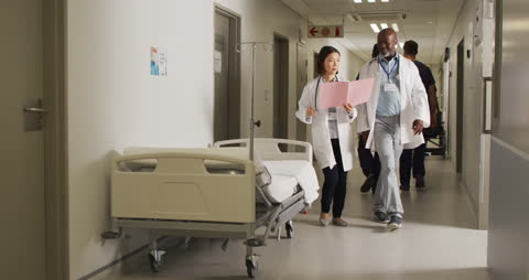 Diverse Medical Team Walking and Discussing in Hospital Corridor