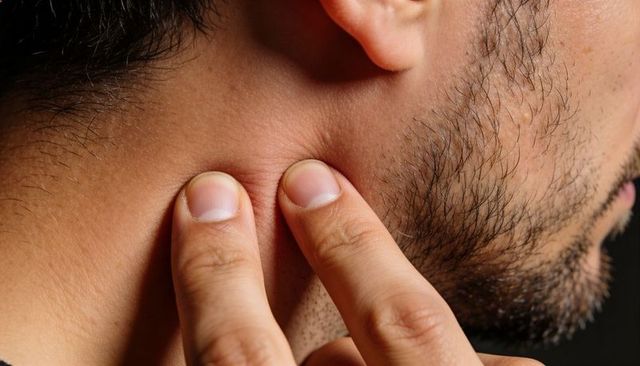 Pressing jawline and neck with fingers close-up showing beard stubble and skin texture