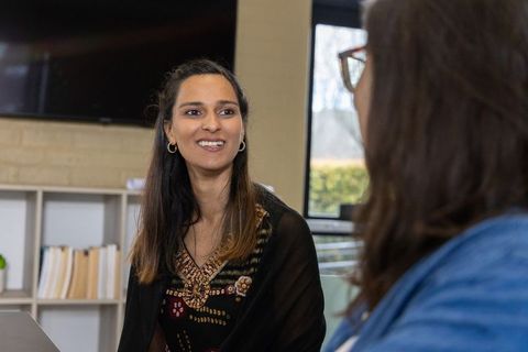 Two women conversing in office lounge wearing embroidered top and shawl