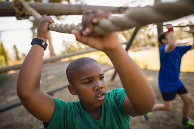 Boy crossing the rope during obstacle course in boot camp