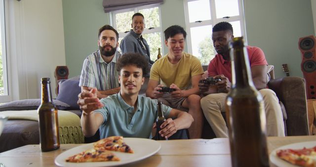 Happy diverse male friends watching tv and drinking beer in living room - Download Free Stock Photos Pikwizard.com