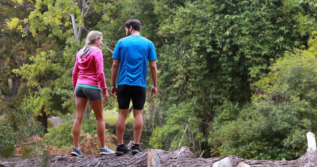 Young man and woman hiking in dense forest, enjoying the scenic nature. Great for themes around outdoor activities, healthy lifestyles, couples bonding, nature adventures, and fitness. Suitable for websites, blogs, travel guides, and environmental initiatives.