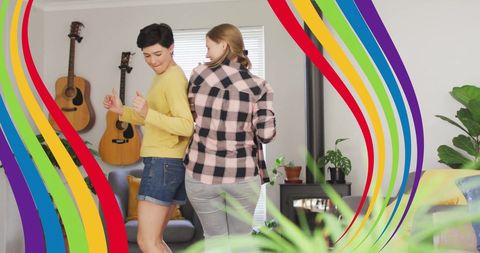 Joyful Lesbian Couple Dancing at Home with Pride Rainbow