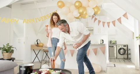 Mature Couple Celebrating Anniversary with Wine in Festive Kitchen