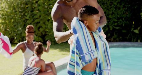 Father Helping Son Dry with Towel After Swimming at Poolside