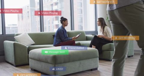 Two women collaborating on tablet in modern office lounge with notification overlays