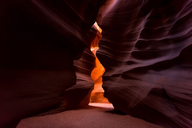 Dramatic view of Antelope Canyon's narrow passages illuminated by sunlight creating a stunning contrast of shadows and vibrant hues. This natural wonder is ideal for promoting travel destinations in Arizona, illustrating geological formations, or adding an adventurous vibe to travel blogs and guides.