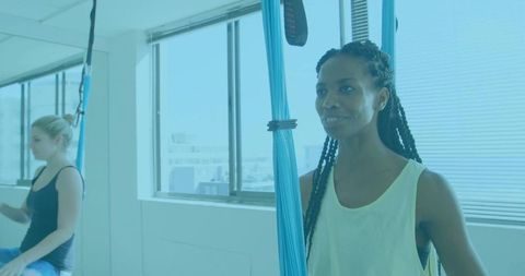 Woman practicing aerial yoga swing in bright urban studio