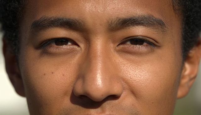 Sunlit closeup headshot of man making direct eye contact showing skin texture and warmth