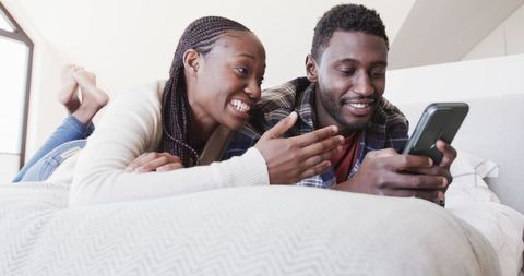 Couple Relaxing on Bed with Smartphone in Bright Bedroom