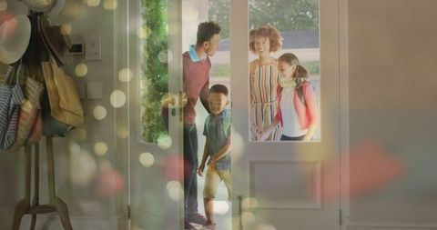 Cheerful family entering home with luggage and coats