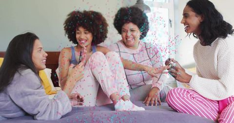 Four friends enjoying pampering manicure and laughter during cozy pajama sleepover