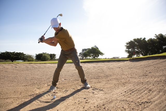 Caucasian male golfer practicing his swing on a sunny day, wearing a cap and golf clothes. Ideal for use in content related to sports, outdoor activities, healthy lifestyle, leisure, and golfing techniques. Perfect for articles, advertisements, and promotional materials for golf courses, sportswear brands, and fitness blogs.