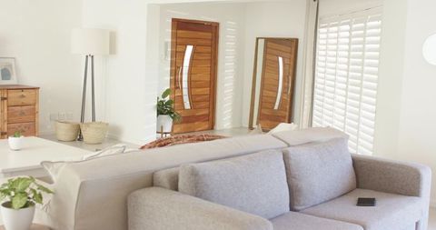 Minimal scandinavian living room with light gray sofa, wooden front door reflection
