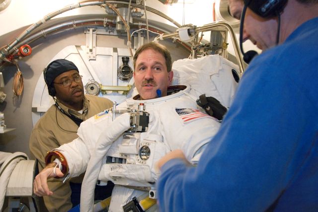 JSC2008-E-006306 (22 Jan. 2008) --- Astronaut John M. Grunsfeld, STS-125 mission specialist, participates in an Extravehicular Mobility Unit (EMU) spacesuit fit check in the Space Station Airlock Test Article (SSATA) in the Crew Systems Laboratory at the Johnson Space Center. Astronaut Michael T. Good (right), mission specialist, and United Space Alliance (USA) suit technician James Lemmon assisted Grunsfeld.