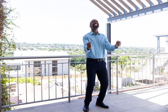 African American businessman celebrating success outdoors. Ideal for business success stories, corporate motivational material, professional achievements, and workplace positivity.