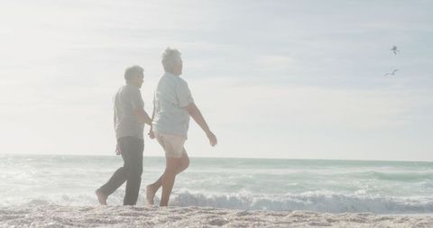 Senior Couple Walking on Beach at Sunset in Romantic Moment