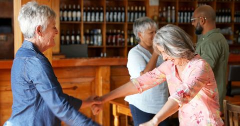 Senior Women Dancing Joyfully in Rustic Cafe Setting
